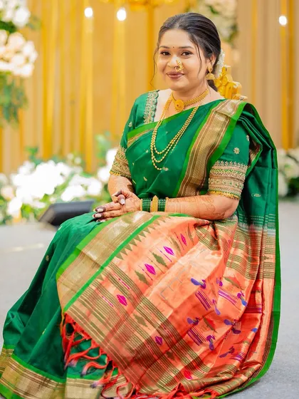 A beautiful bride seated gracefully in a traditional green Paithani saree, her makeup soft and elegant.