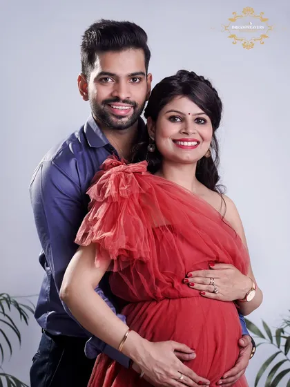 A classic studio portrait of a smiling couple, beautifully lit to highlight the mother's baby bump. We aim to create photos that are both elegant and full of genuine happiness.