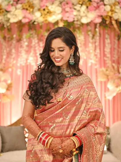 A candid, smiling portrait of the bride at her reception. Her soft curls and glowing makeup create a look of effortless glamour.