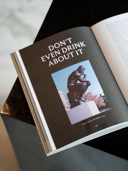 A page from an Armani Libri book with the witty phrase 'Don't Even Drink About It' over an image of 'The Thinker.' We offer a curated collection of these books celebrating art, fashion, and luxury.