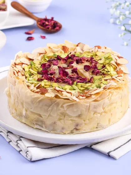 This is my fusion creation, the Baklava Cheesecake. It combines the creamy texture of cheesecake with the crispy, nutty, honey-soaked layers of traditional baklava, garnished with pistachios and rose petals.