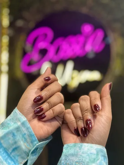 Both hands are showcased here, displaying the rich and consistent color of this classic red manicure against the salon's signature background.