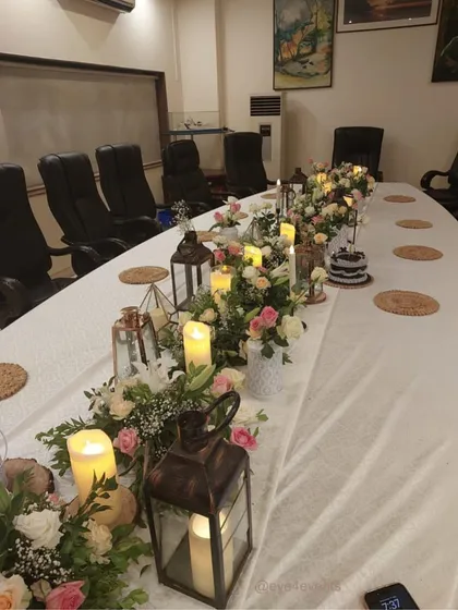 We can transform any space, even a corporate conference room, into a beautiful dining area. Here, we used a floral runner with rustic lanterns and candles to soften the room and create a warm, celebratory atmosphere.