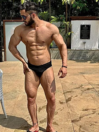 A relaxed pose by the pool. Even when not flexed, a well-conditioned physique shows clear muscle definition and low body fat.