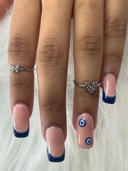 A closer view of the evil eye and French tip combination, showing the clean lines and detailed artwork.