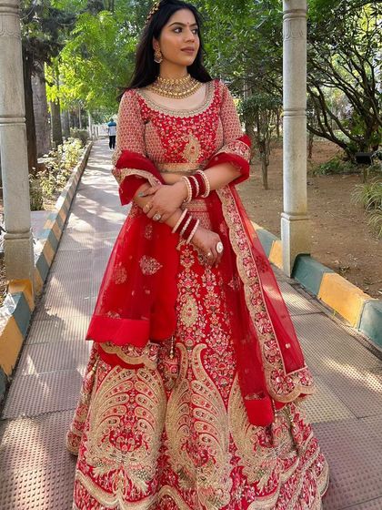 A full-length shot of a gorgeous bride in a red lehenga. This classic North Indian bridal look is perfect for a reception, combining tradition with modern elegance.