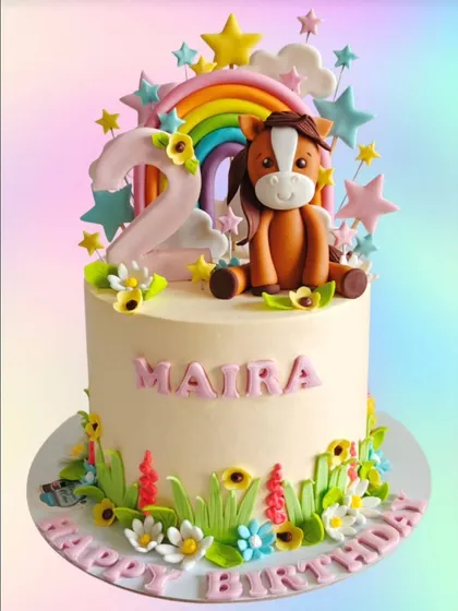 A sweet horse and rainbow-themed cake for a 2nd birthday. This design features a cute fondant horse, a pastel rainbow, and delicate wildflowers.