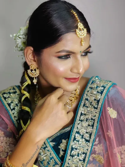 The complete look, featuring a sleek braid adorned with fresh flowers. The makeup is balanced, with defined eyes and a warm lip color that perfectly suits her skin tone.