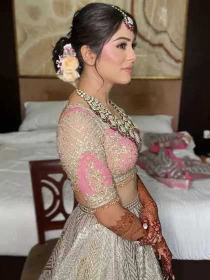 A side profile of a bride with a soft, textured updo adorned with a few flowers. This is a beautiful and modern take on the classic bridal bun.