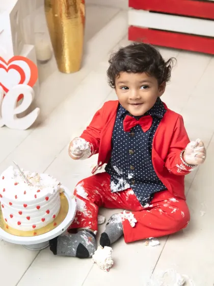 A Valentine's Day themed cakesmash is full of love. This little boy looks so dapper in his red suit, ready to celebrate his first birthday with a heart-dotted cake.