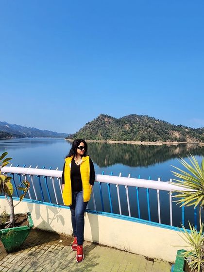Welcoming the new year with a view. A bright yellow puffer vest adds a pop of color to this winter travel look by the lake.