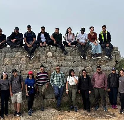 A group photo against a historic stone wall on the Kaiwara Hills trail.