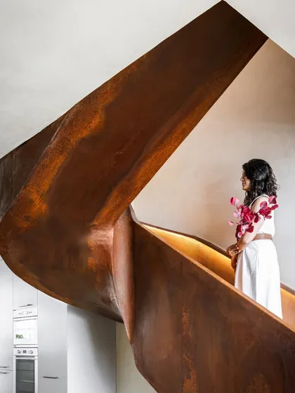 At the heart of the Terra Gardens apartment, a sculptural staircase crafted from Corten steel serves as a functional work of art. Its raw, weathered finish and sweeping form create a powerful focal point that connects the home's levels with architectural grace.