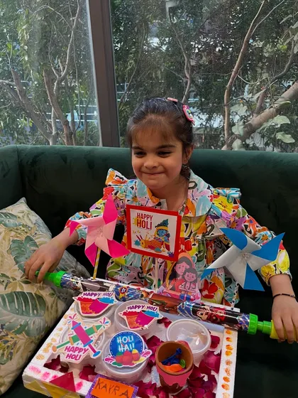 Getting into the Holi spirit! This student is all smiles with her handmade Holi platter, complete with a pichkari, pinwheels, and organic colors.