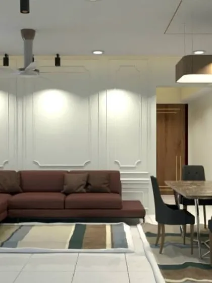A look at the spacious living room with a rich brown L-shaped sofa. The white wall paneling and strategic spotlights create a bright and welcoming atmosphere.