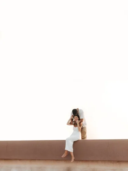 A minimalist composition focusing on a tender moment. The vast, bright background emphasizes the couple's closeness, creating an artistic and modern pre-wedding portrait.