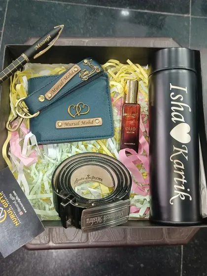This grand hamper includes a personalized wallet, keychain, belt, pen, flask, and a perfume, all customized with names.