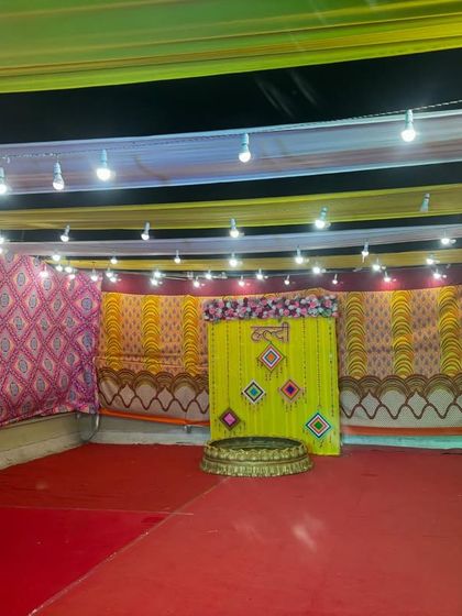 A wide-angle shot showing the scale of the Haldi venue decoration. We ensure the entire space, including the ceiling with draped fabric and lights, is part of the theme.