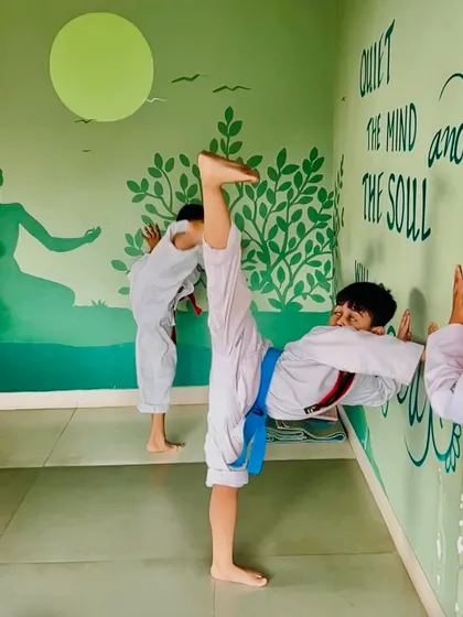 A student uses the wall to deepen his split stretch, a common technique we use to safely improve flexibility.