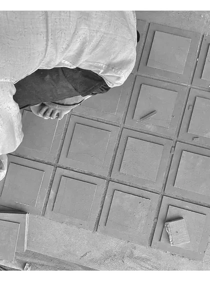 A craftsman carefully lays out custom-cut tiles. This black and white shot captures the hands-on effort and skill that goes into creating the unique details of our projects.