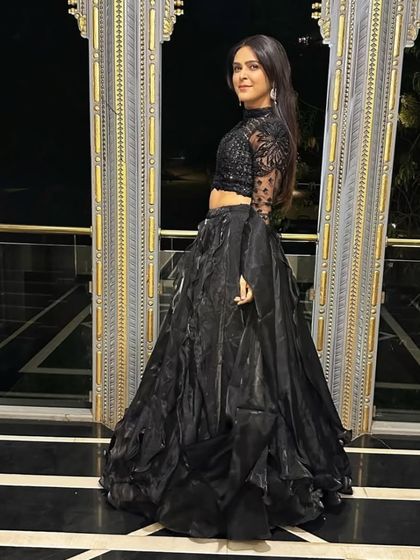 A full-length shot against an ornate background, emphasizing the grand and glamorous feel of this black lehenga gown.