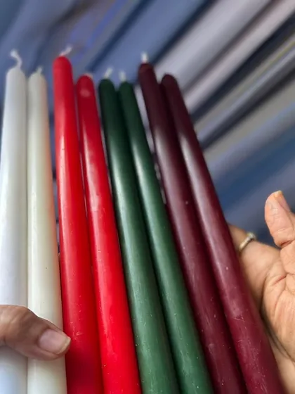 Holding a handful of my handmade tapered candles. You can feel the quality and craftsmanship in each one.