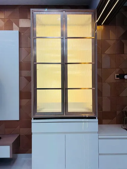 A mandir with fluted glass doors, shown closed. The warm light from within creates a soft, mysterious glow.