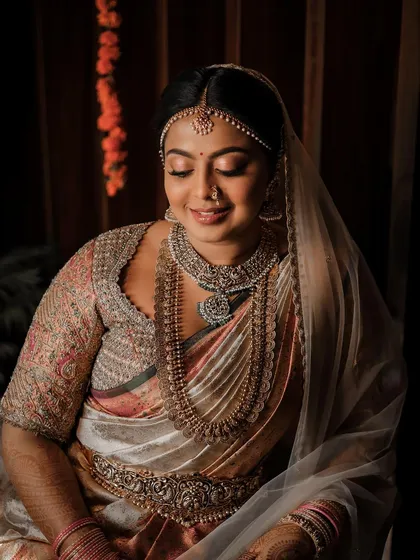 A serene portrait of a bride on her wedding day. Her custom blouse features intricate embroidery that complements her traditional Kanchipuram saree and layered temple jewelry.