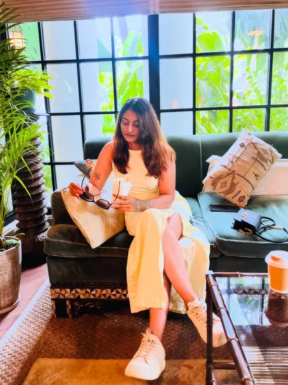 Relaxing in a comfy spot. This wider shot shows how the yellow dress and white sneakers create an effortlessly cool and casual look.