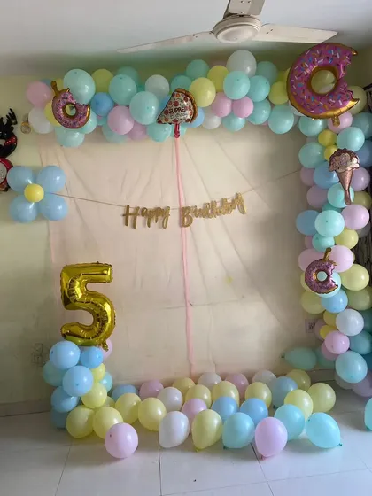 A sweet and simple donut and ice cream themed birthday at home. This pastel-colored balloon arch is decorated with fun foil balloons and a 'Happy Birthday' banner.