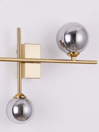 A modern wall sconce with two smoked chrome globes on a brass fixture. The mix of metals creates a sophisticated, contemporary look.