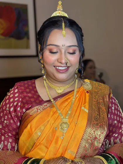 A close-up of the bride's dewy makeup, showing how it complements her traditional gold jewelry and saree.