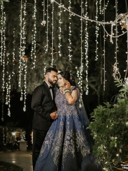A romantic night-time portrait of the couple under a curtain of fairy lights, creating a magical and intimate setting.
