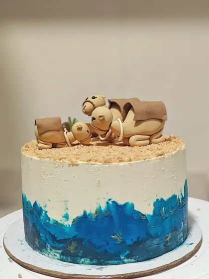 The full camel-themed baby shower cake. I used a blue watercolor effect on the bottom to represent an oasis, adding a pop of color to the design.