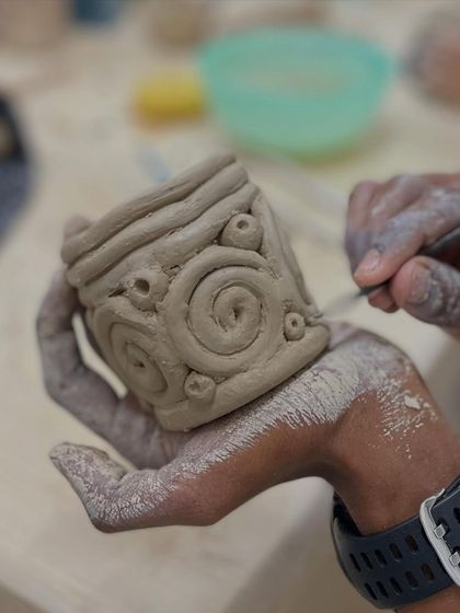 Hand-building allows for incredible detail. This student is carving intricate spiral patterns onto a cup they built by hand.