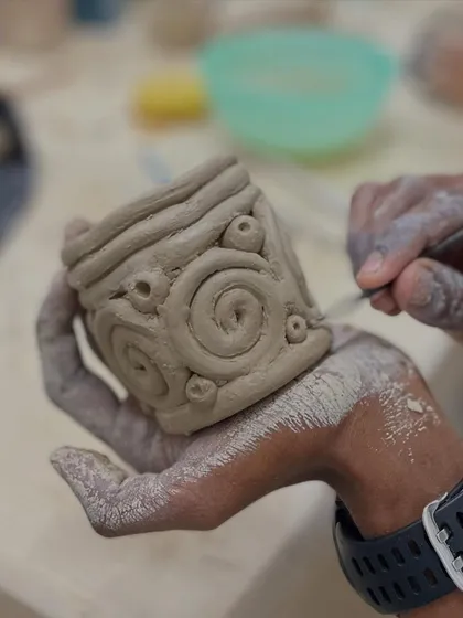 Hand-building allows for incredible detail. This student is carving intricate spiral patterns onto a cup they built by hand.
