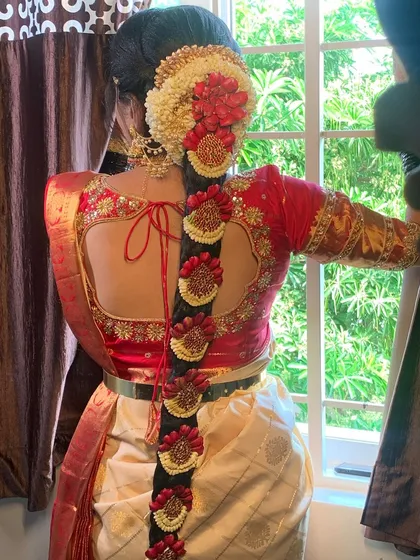 A South Indian bridal look is incomplete without the perfect hairstyle. This is a detailed view of a traditional Poola Jada, intricately woven with fresh flowers and classic hair jewels for a timeless and regal finish.