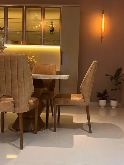 A side view highlighting the elegant profile of the dining chairs and the warm, inviting glow from the decorative wall light.