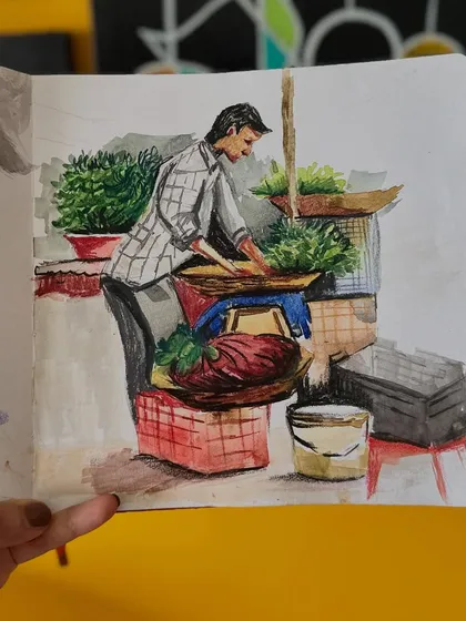 A different angle of my sketchbook, showing the painting of the vegetable vendor. The open sketchbook format allows me to create a narrative spread.