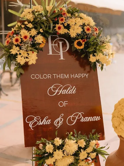 A custom Haldi sign decorated with yellow chrysanthemums and sunflowers, setting a cheerful tone for the event.