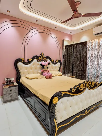 A beautiful girl's bedroom with a pink accent wall featuring elegant arch-shaped grooves. The classic black and white carved bed adds a touch of royal charm to the room.