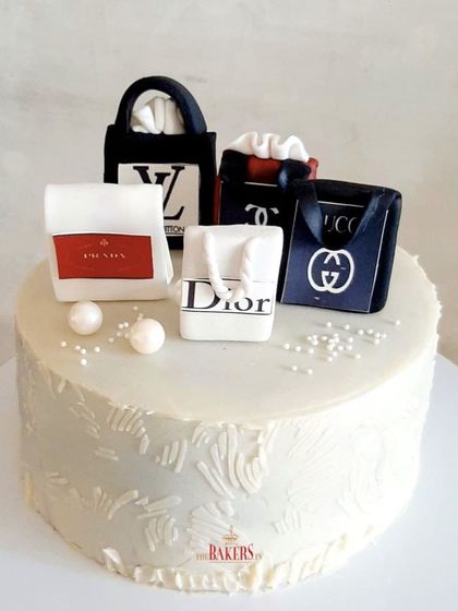 For women who love to shop! This minimal-fondant cake features a textured white base and is topped with a collection of edible luxury shopping bags from brands like Dior, LV, and Prada.