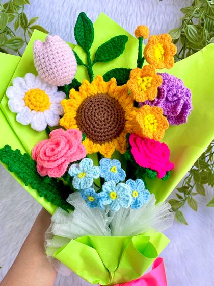 A close-up, in-hand view of the vibrant mixed flower bouquet. You can see the different textures of the sunflower, rose, tulip, and forget-me-nots.