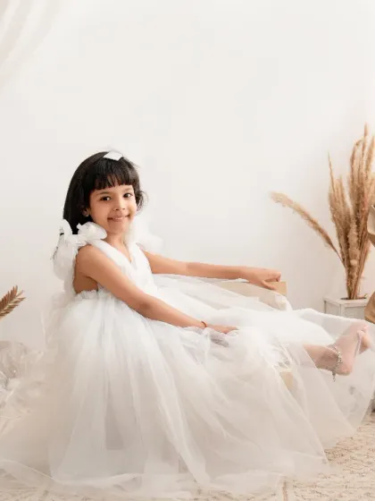 A bow at the back and a world of wonder ahead. This girl looks so elegant in her white dress, part of a clean and modern setup.