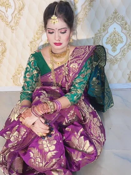 A full-length view of a client in a traditional Maharashtrian look for a festival. The purple and gold saree is complemented by classic makeup and a simple hair updo.