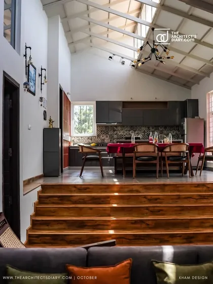 Natural light streams in from the skylights in the vaulted ceiling, illuminating the dining and kitchen area. The open-plan layout and high ceiling create a sense of spaciousness and connection to the outdoors.