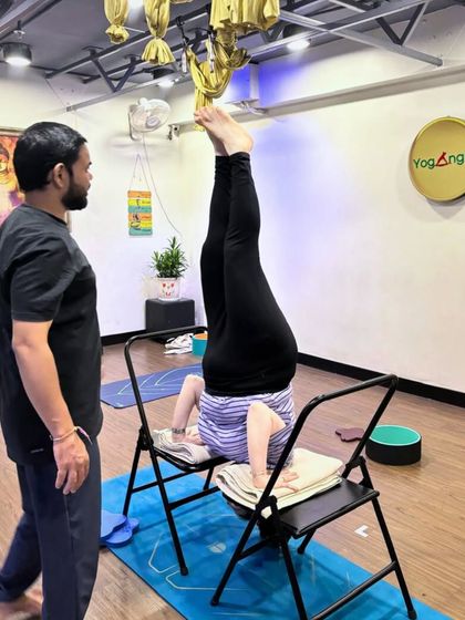 With expert coaching and the right props, poses that once seemed impossible become achievable. Here, I am spotting a student as she practices a supported headstand using two chairs for stability.
