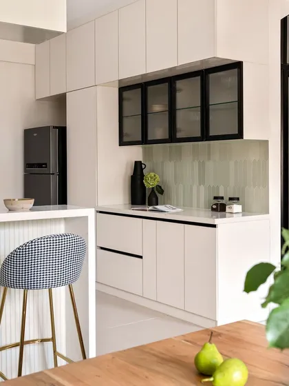 This kitchen design uses a sophisticated palette of white, black, and houndstooth. The clean white cabinets are contrasted with black-framed glass uppers, and a breakfast bar with patterned stools adds a chic, graphic touch.