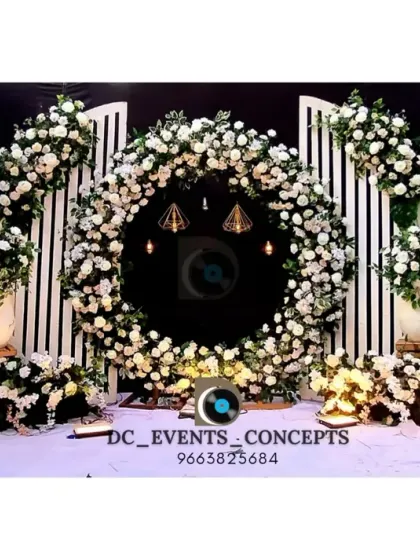 A perfect example of modern elegance for a Mehendi or Sangeet night. The clean white floral ring backdrop, paired with geometric paneling and subtle lighting, offers a chic and sophisticated setting for pre-wedding festivities.