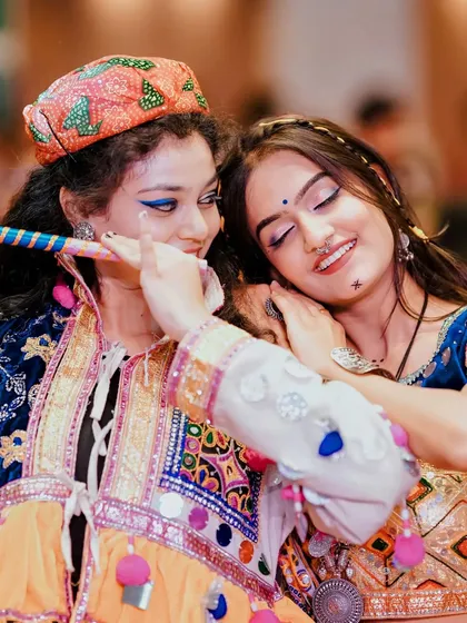 A sweet moment of friendship between two dancers, one resting her head on the other's shoulder amidst the festivities.